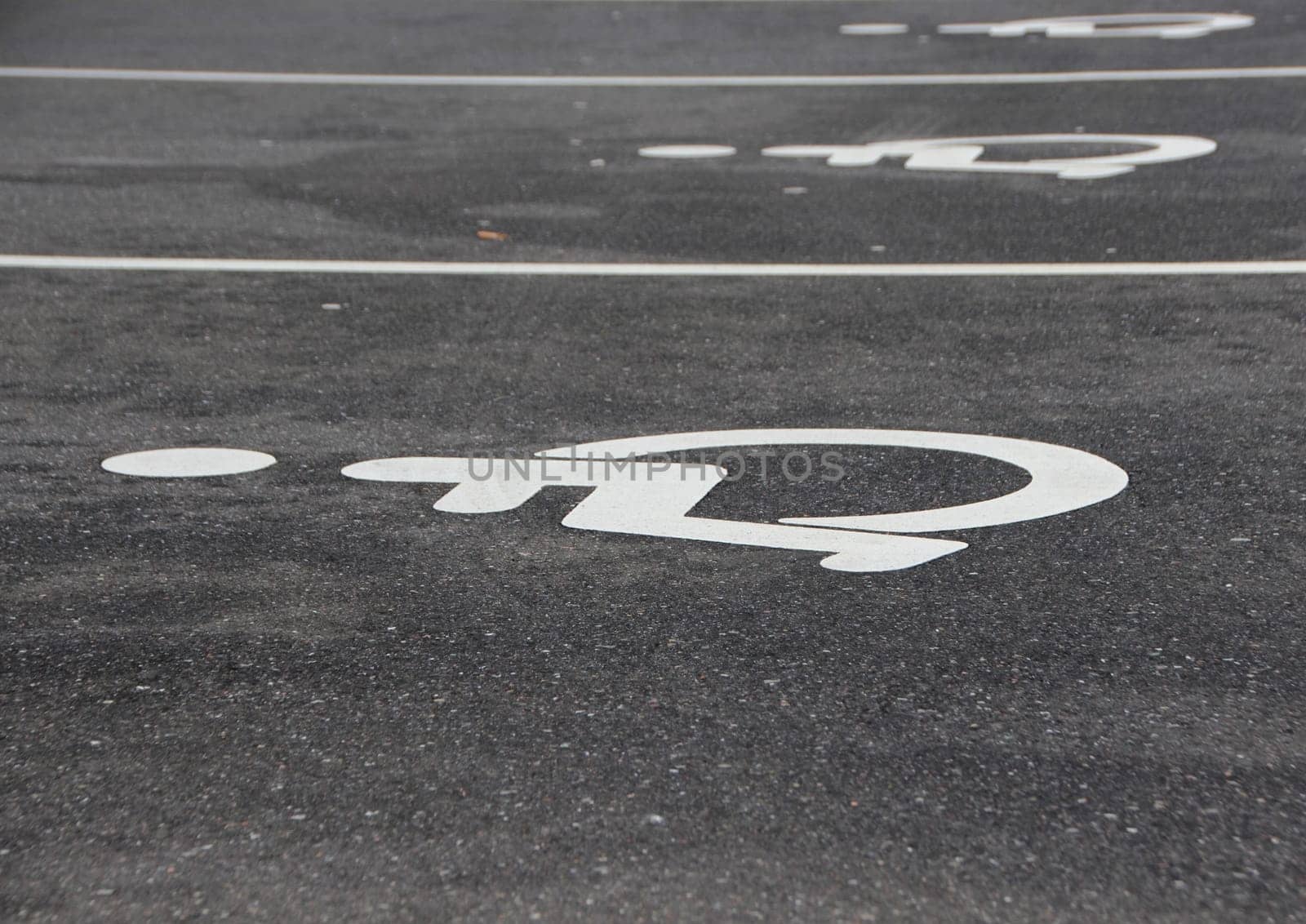 Line of White Handicap Disabled Sign on Black Asphalt