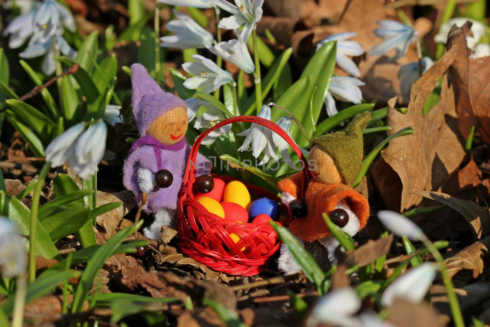 Two small gnomes with Easter eggs under spring flowers