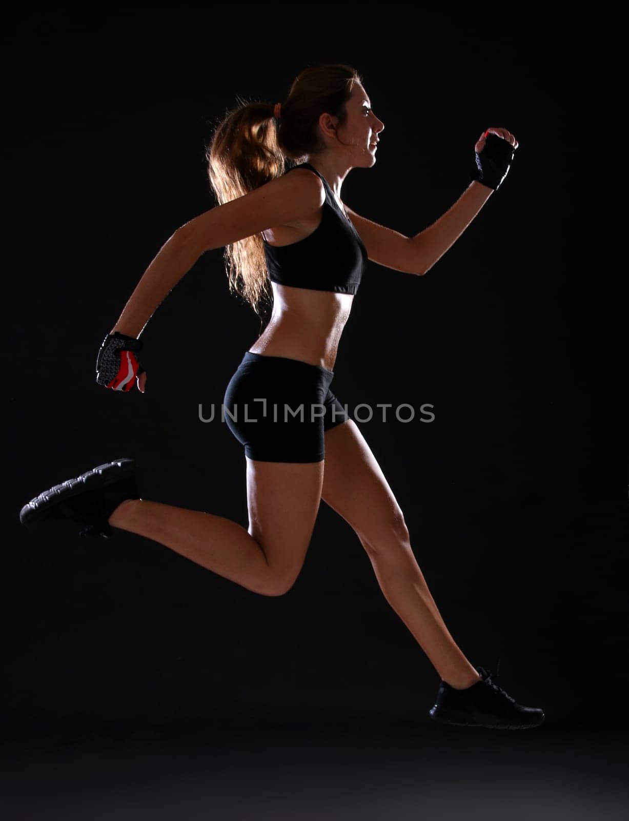 Fitness. Young woman doing exerciseover black background