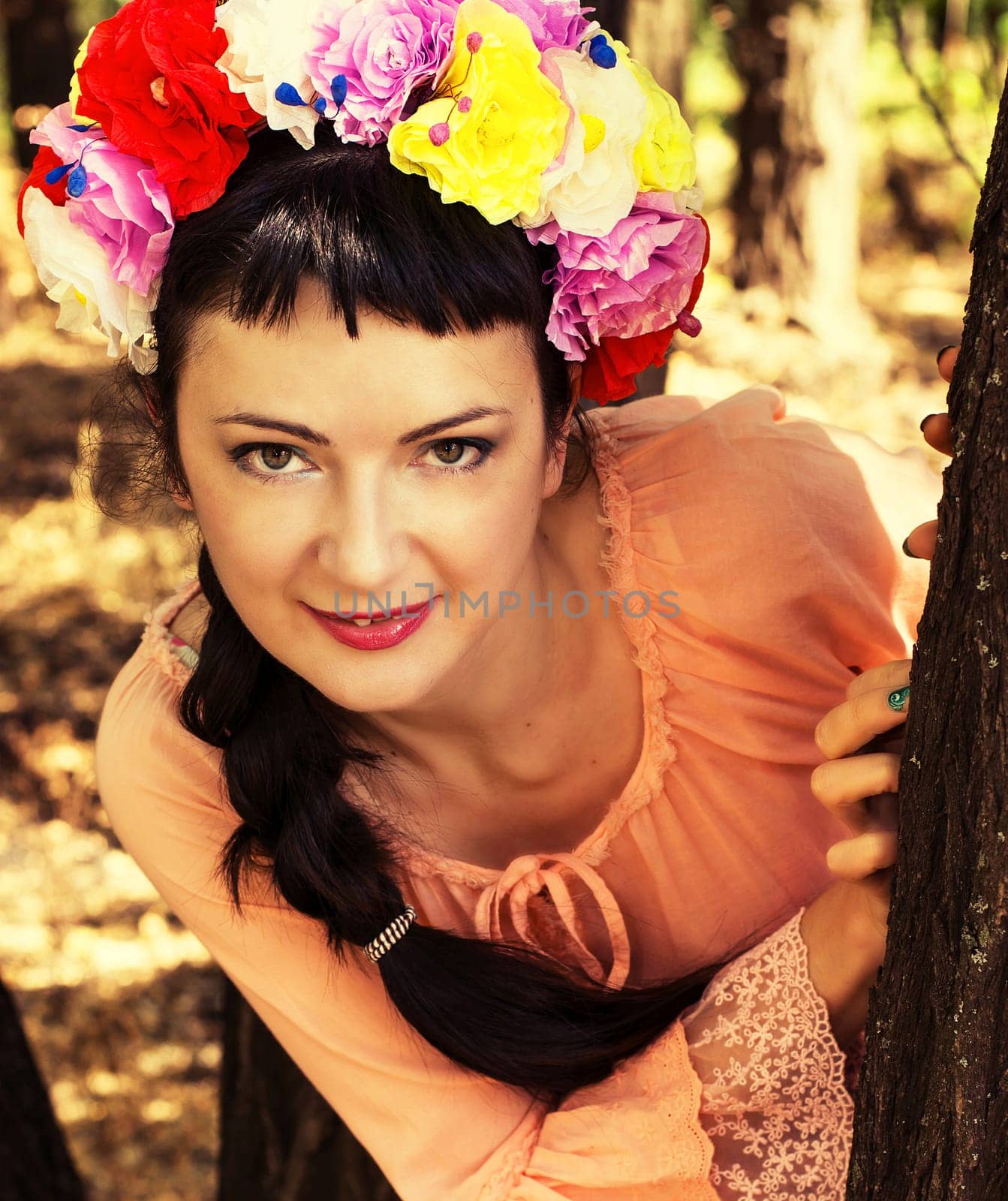charming woman in wreath of roses on her head on the background of nature