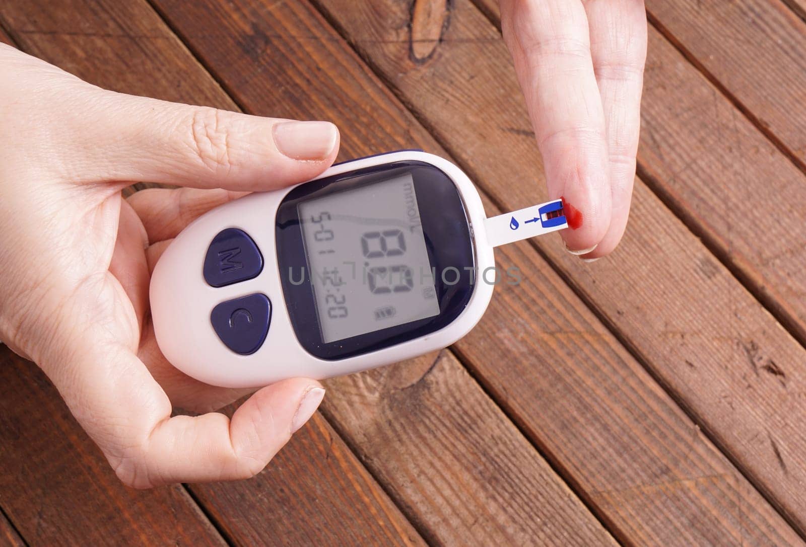 a lady&#39 s hands measuring blood glucose with a home test to control her diabetes