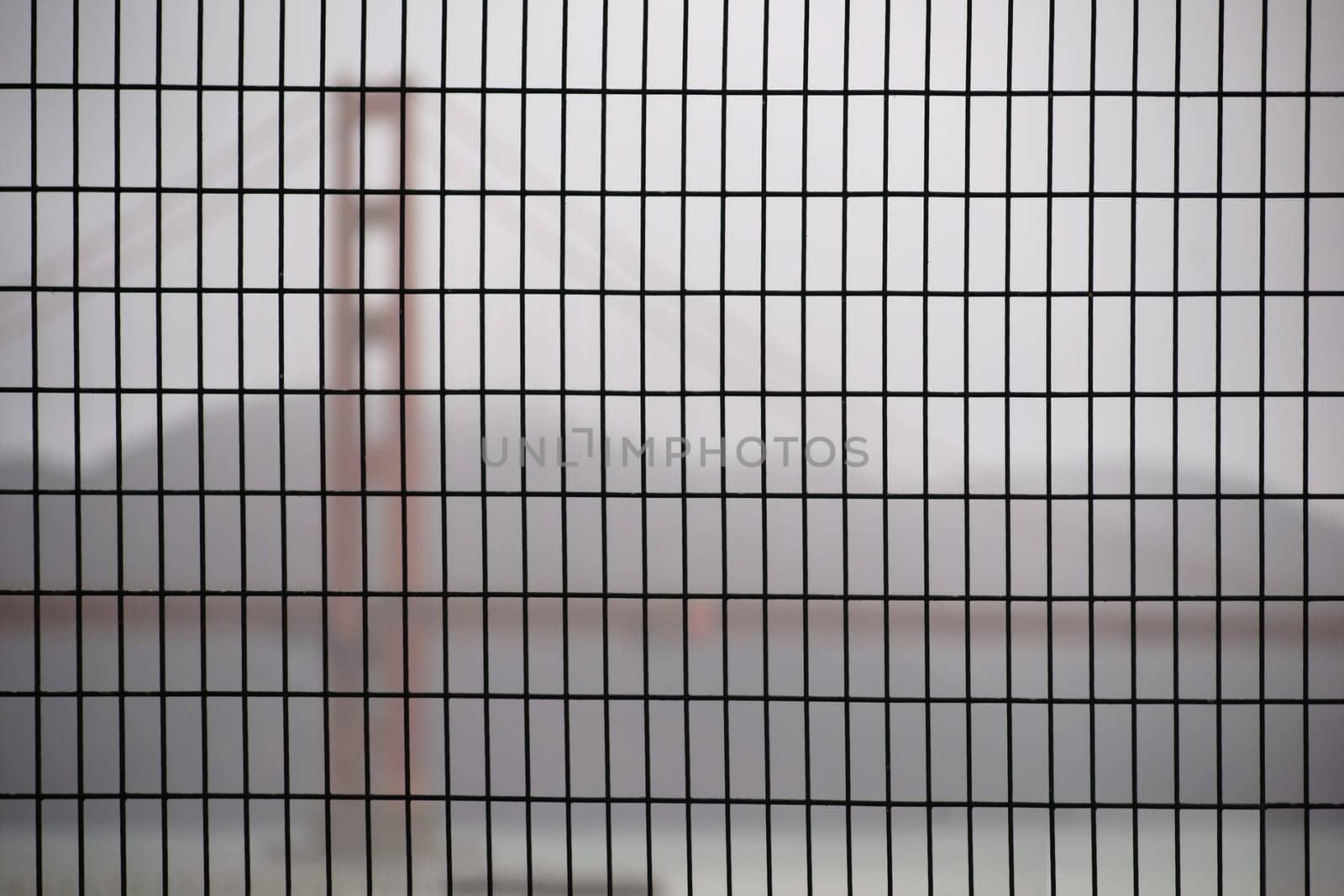 The Golden Gate bridge blurred behind a fence in this rainy weather.