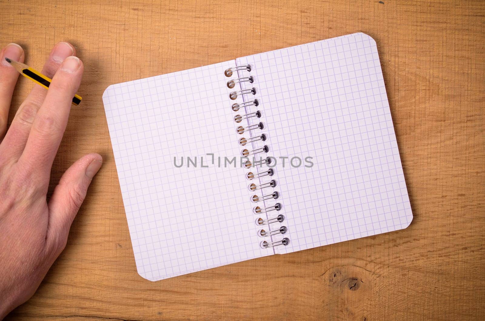 Male hand with a notebook on a wooden table