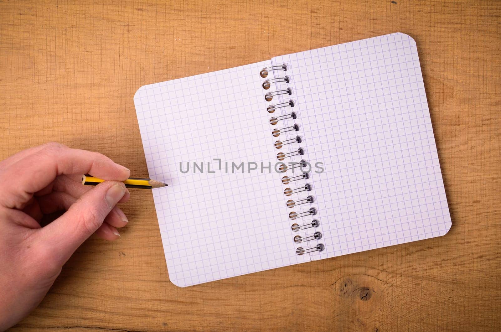 Male hand with a notebook on a wooden table