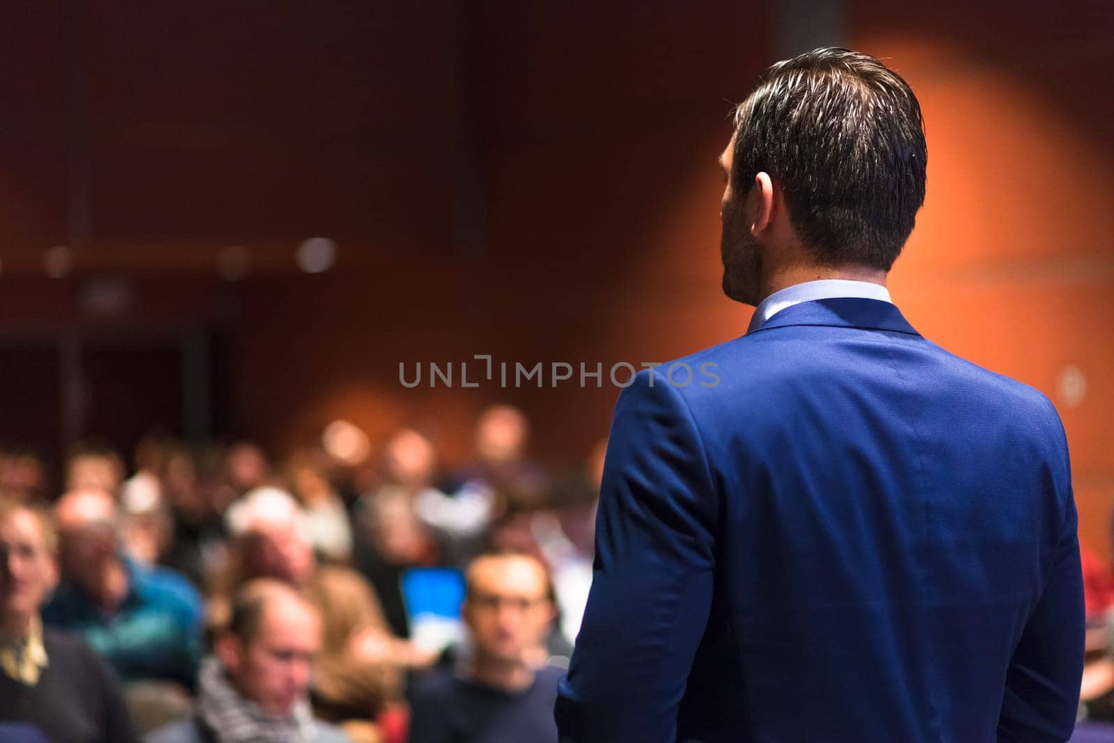 Speaker giving a talk on corporate Business Conference. Audience at the conference hall. Business and Entrepreneurship event.