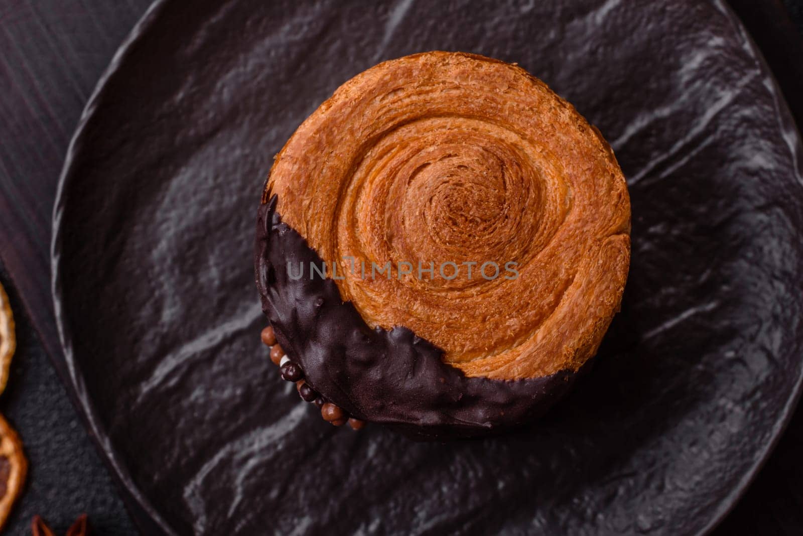 Round sweet New York roll croissant with chocolate cream filling on a dark concrete background