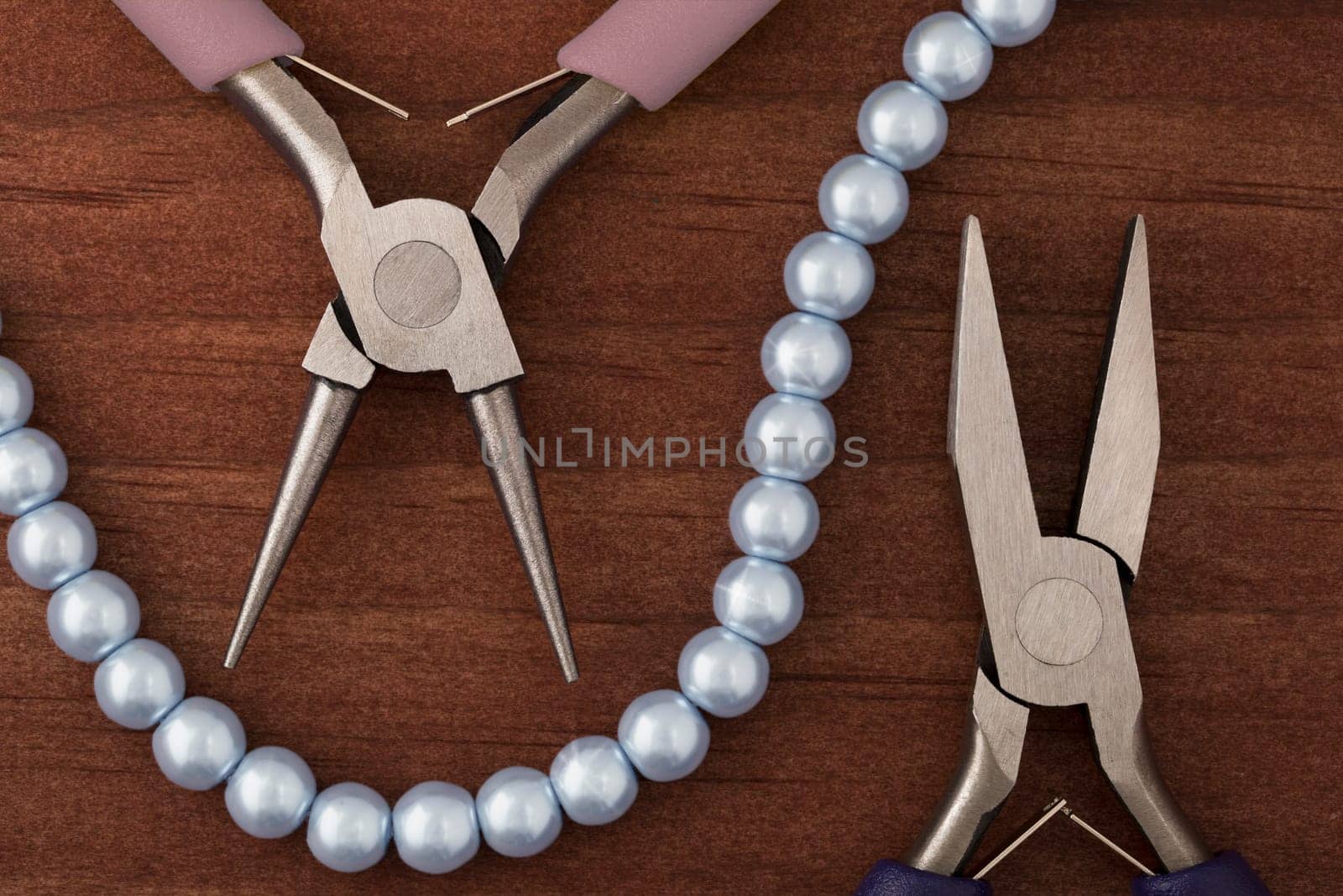 Two types of jewelry making pliers and a string of blue pearls for jewelry making.