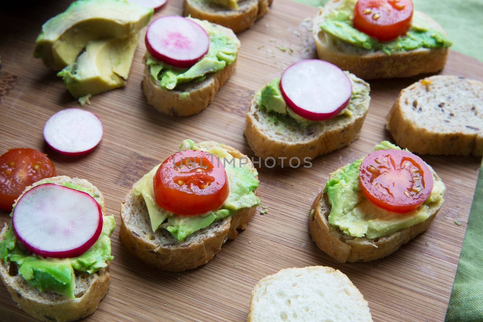 Healthy bites of avocado toast topped with tomato and radish slices.