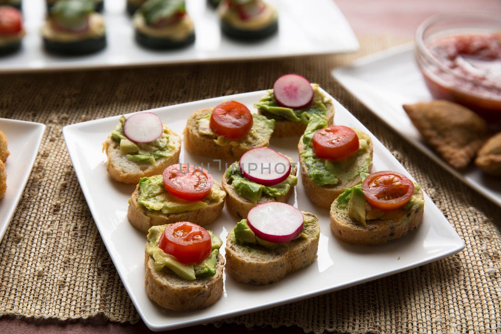 Healthy bites of avocado toast topped with tomato and radish slices.