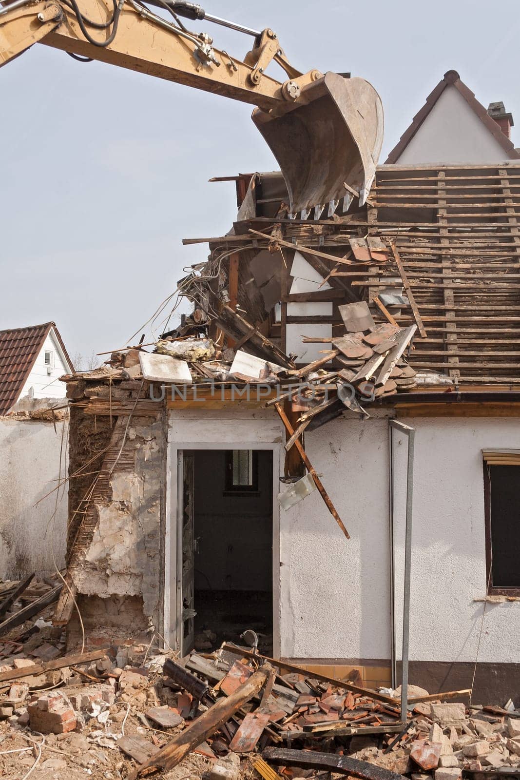 A large track hoe excavator tearing down an old house
