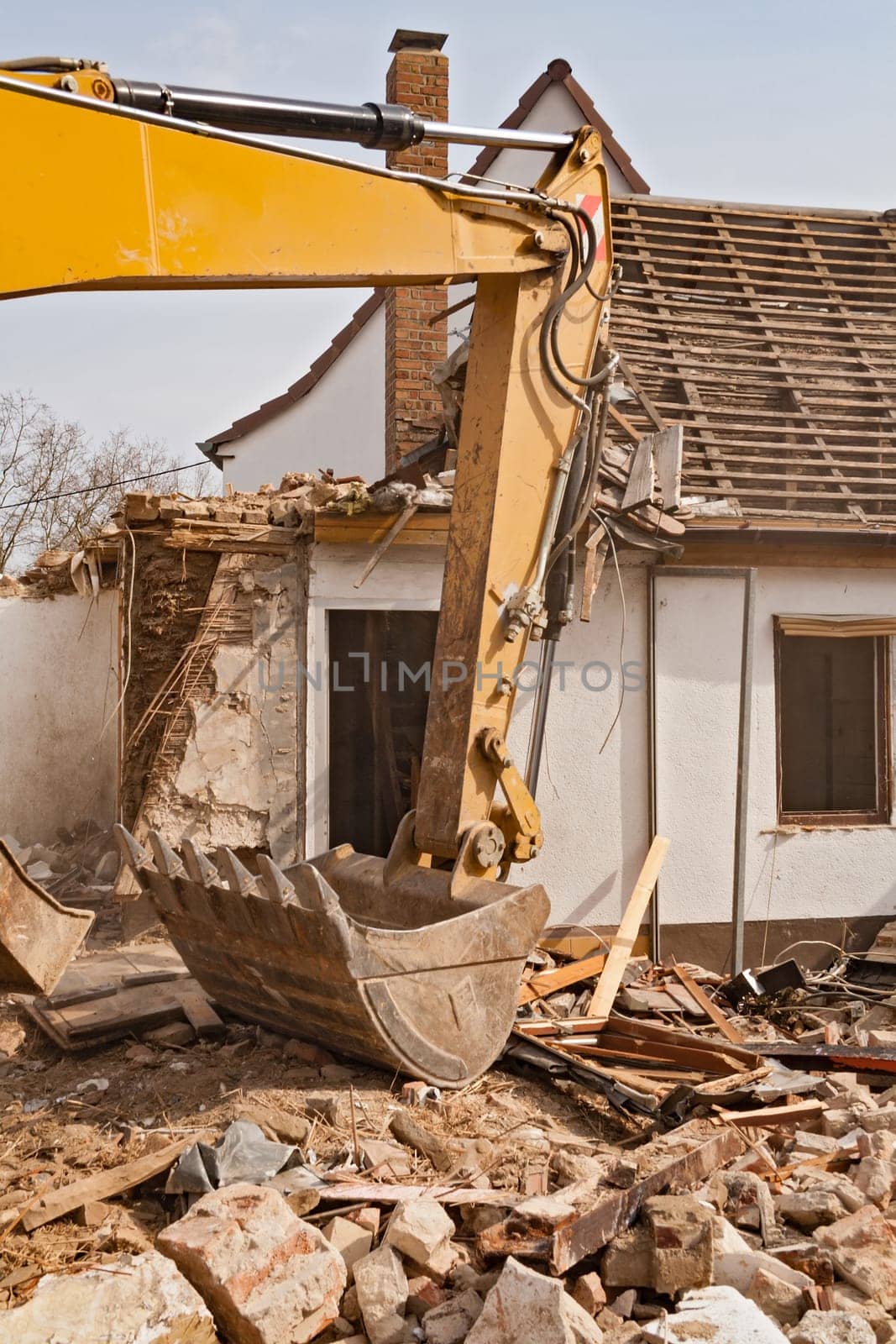 A large track hoe excavator tearing down an old house
