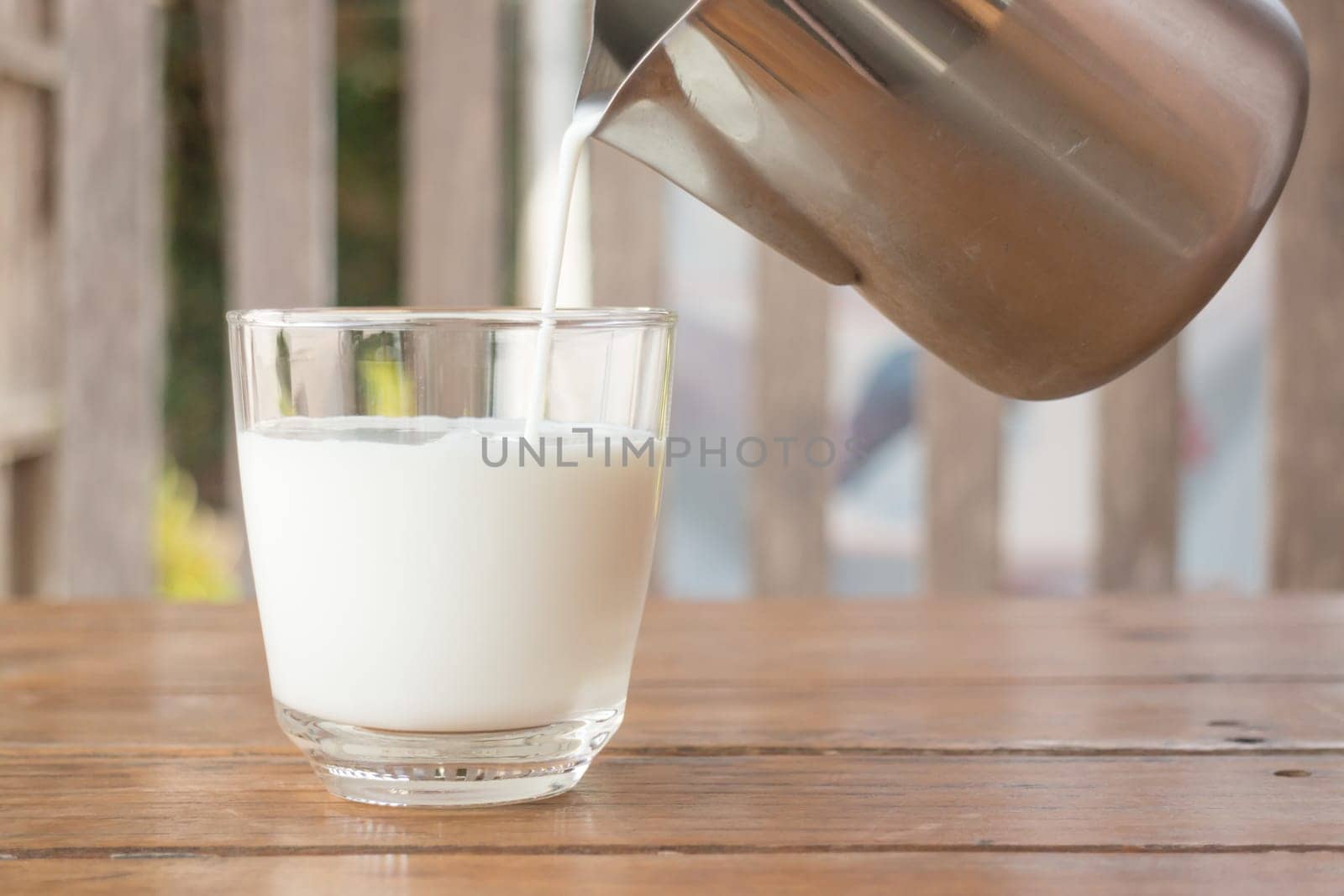 Pour milk from a pitcher into a glass, stock photo
