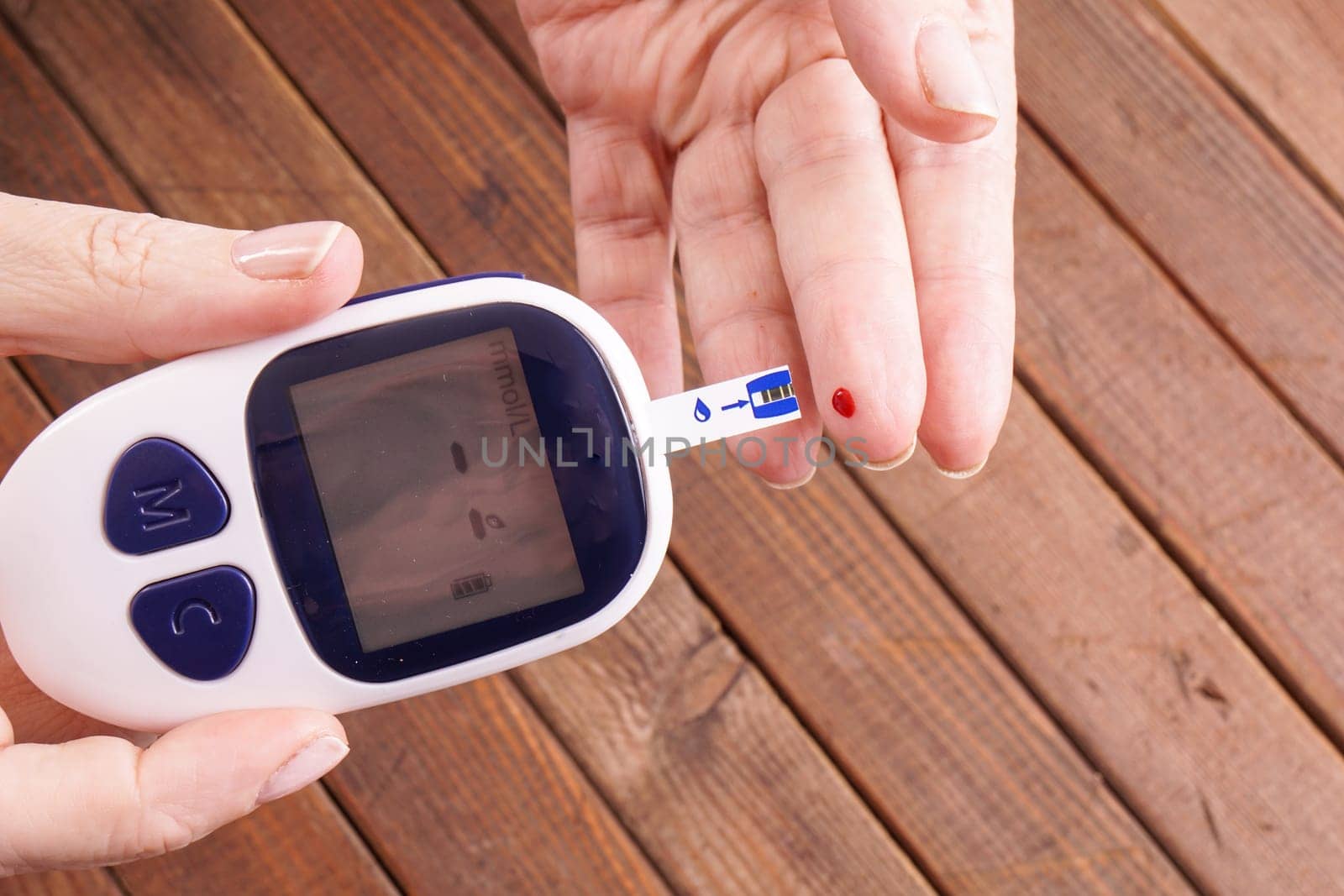 a lady&#39 s hands measuring blood glucose with a home test to control her diabetes