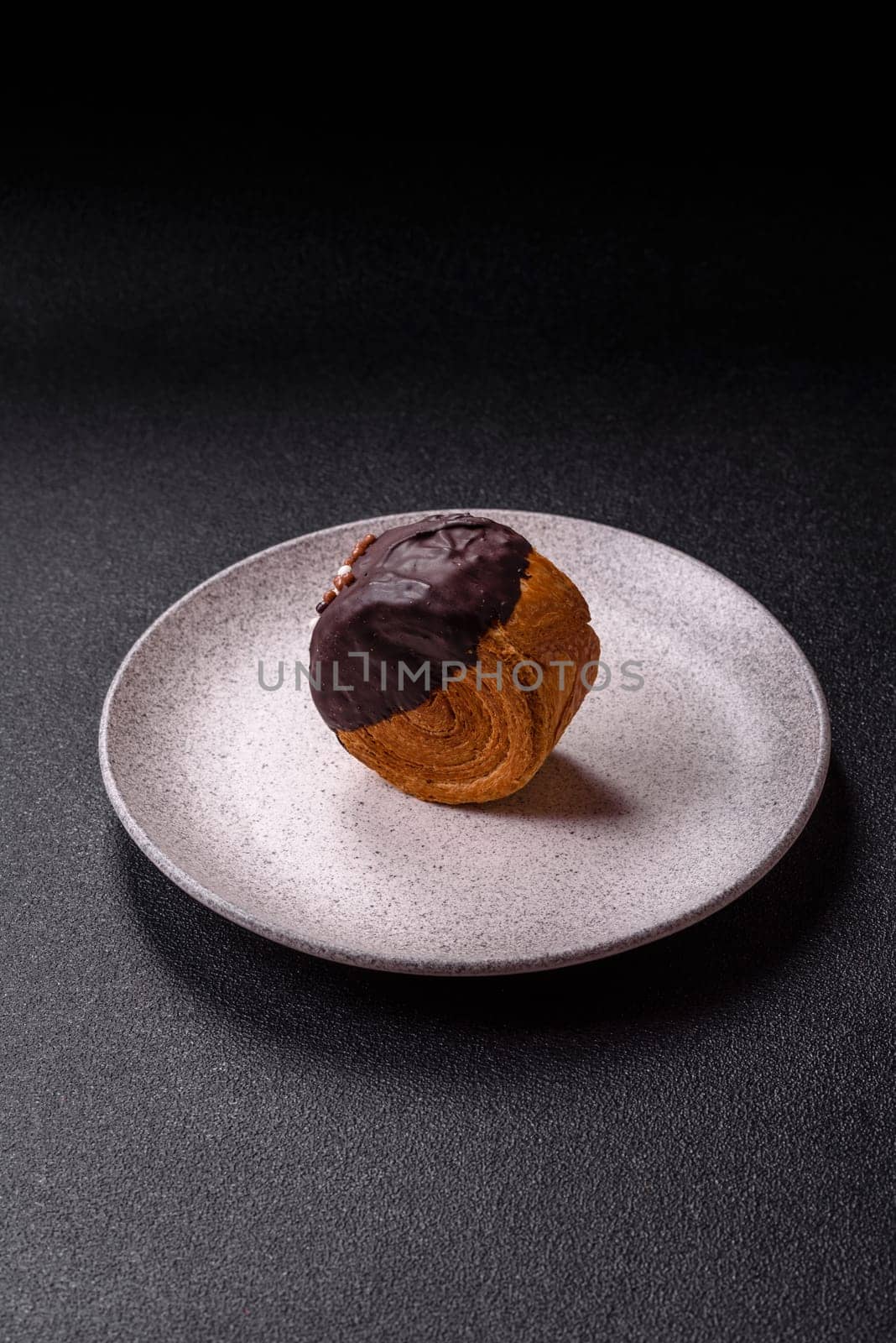 Round sweet New York roll croissant with chocolate cream filling on a dark concrete background