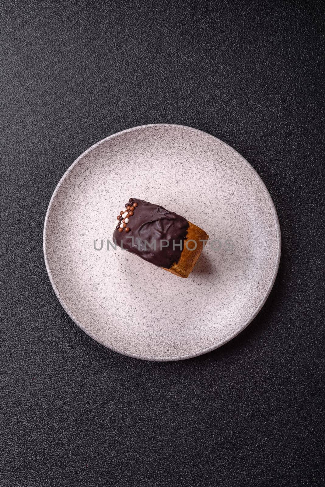 Round sweet New York roll croissant with chocolate cream filling on a dark concrete background