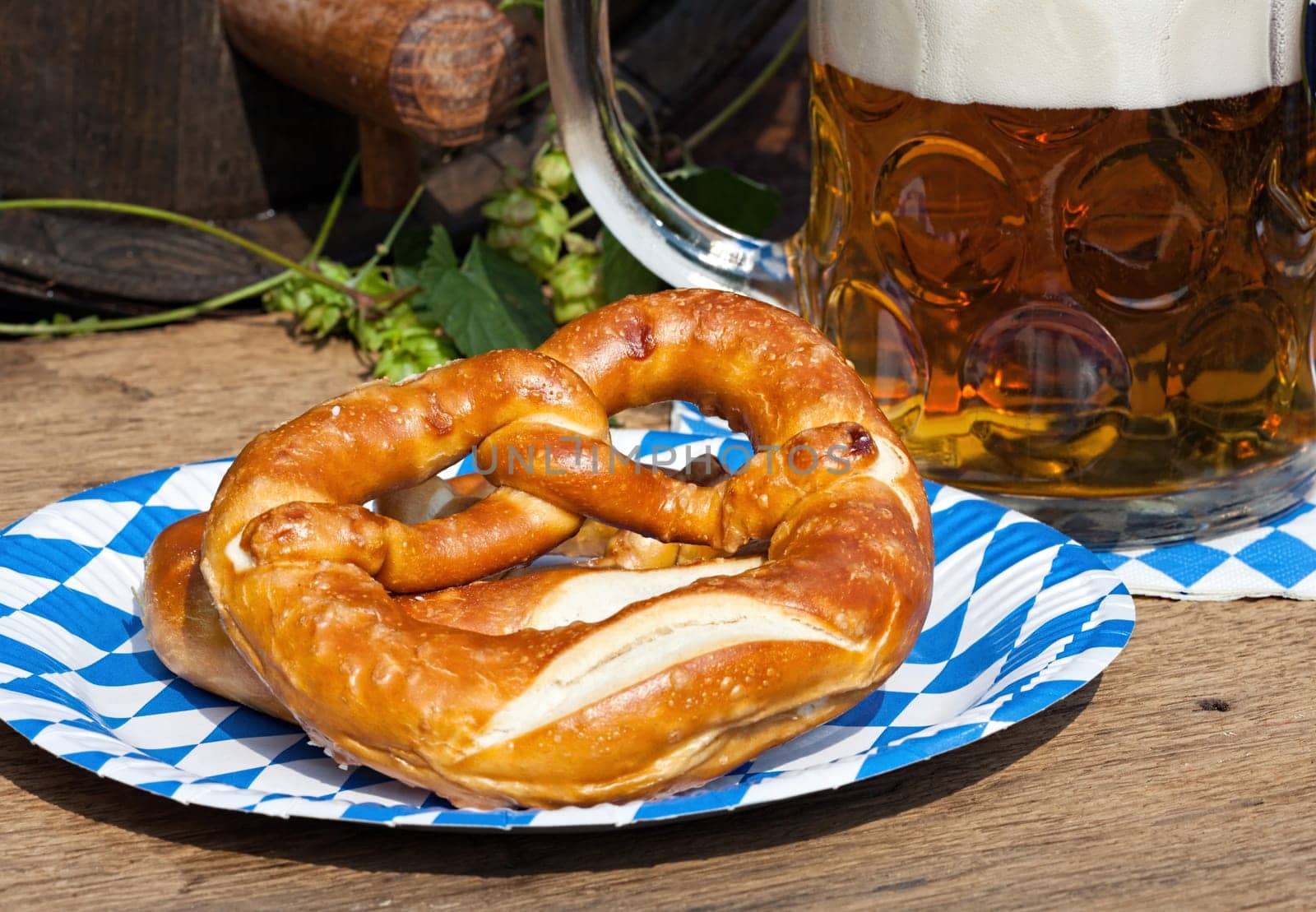 Large glass of beer and pretzel on a paper plate