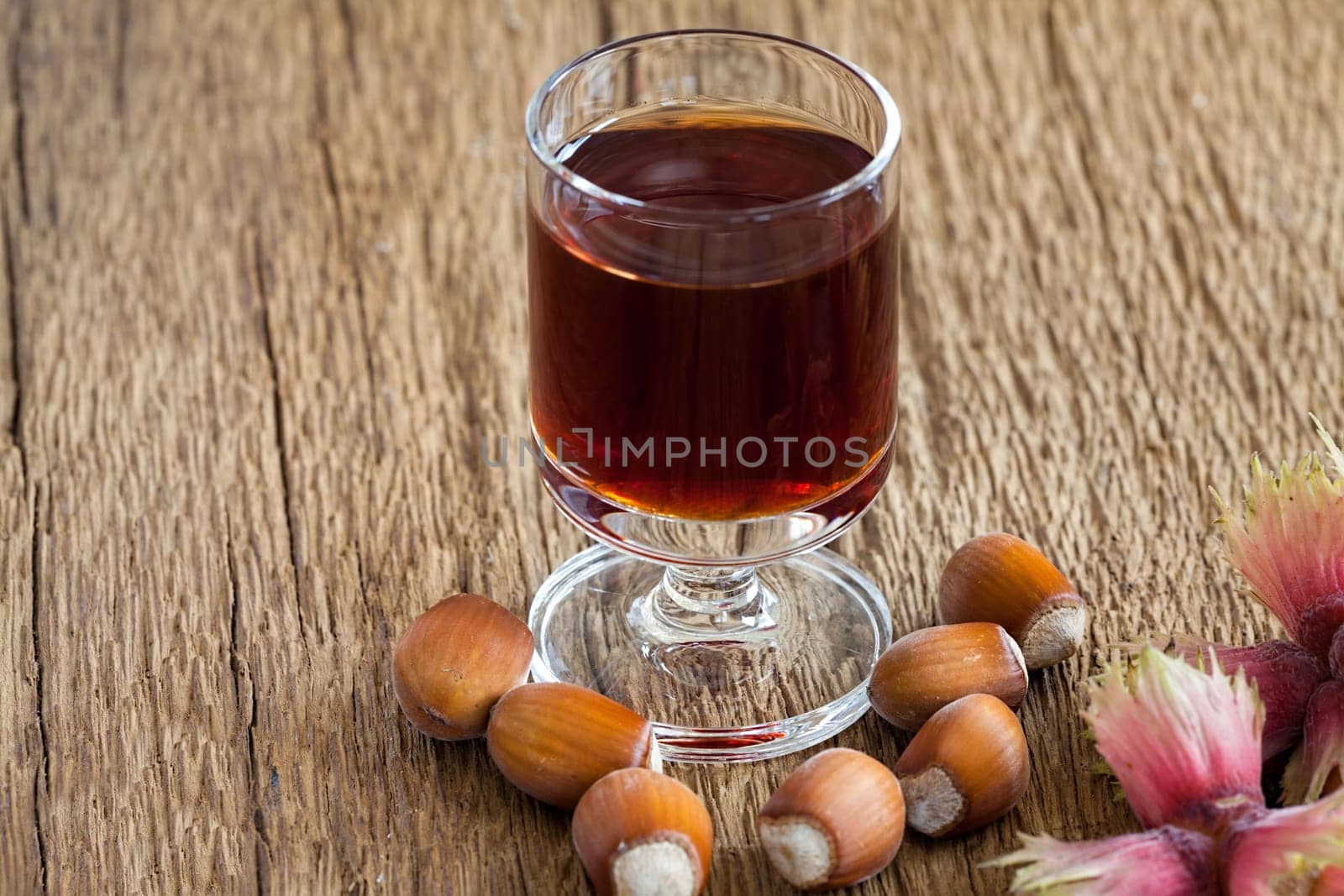 Homemade Hazelnut liqueur in a glass and hazelnuts of an old rustic wooden table