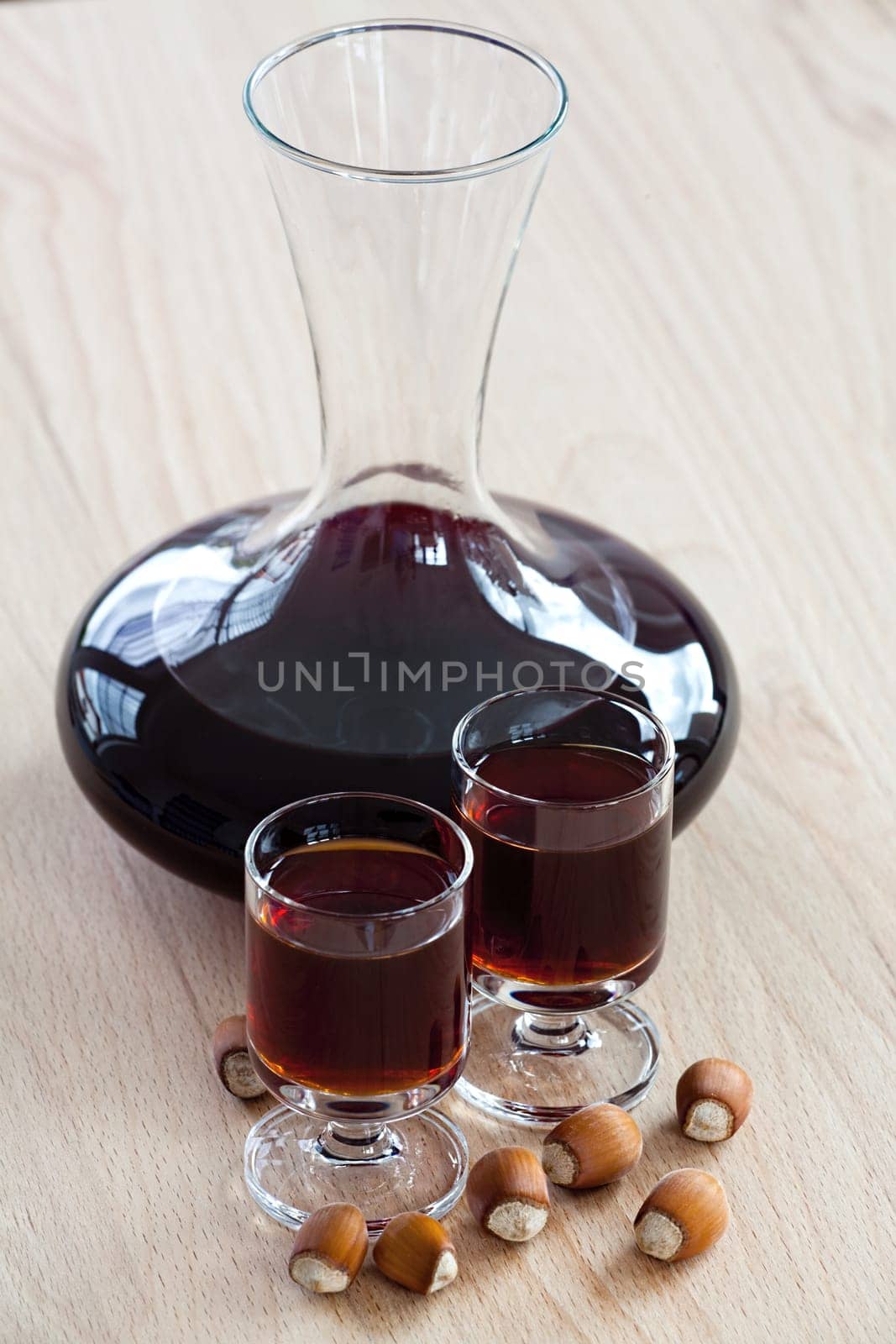 Homemade hazelnut liqueur in a glass carafe on a wooden background