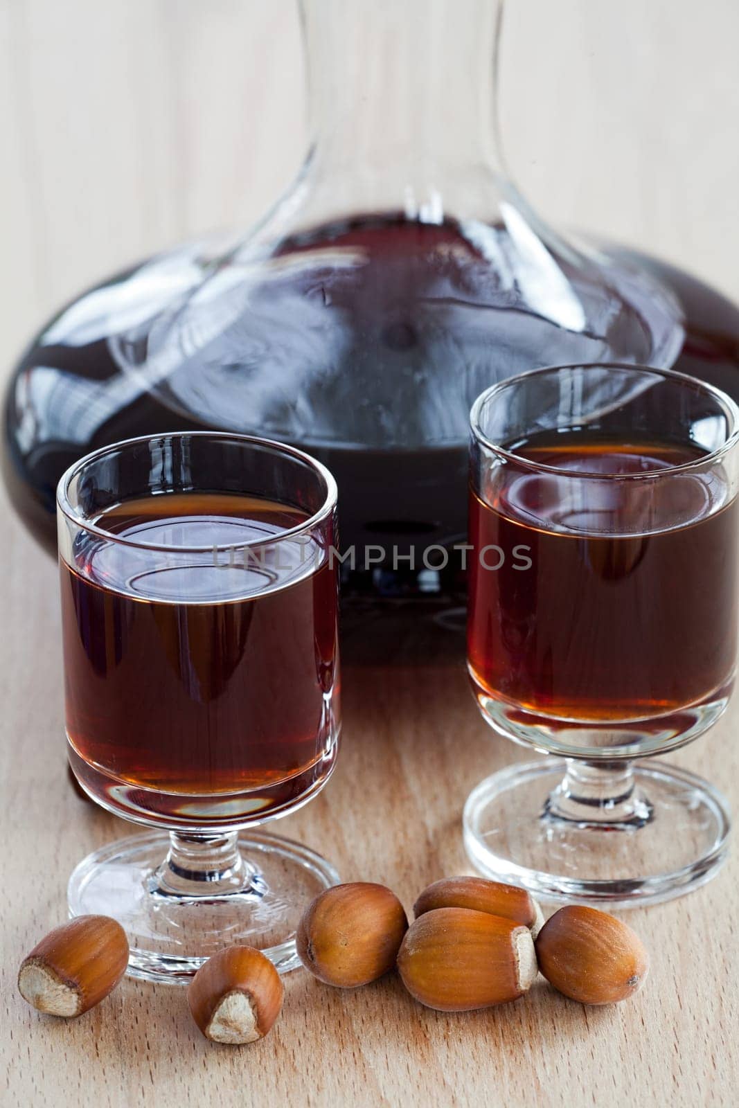 Homemade hazelnut liqueur in a glass carafe on a wooden background