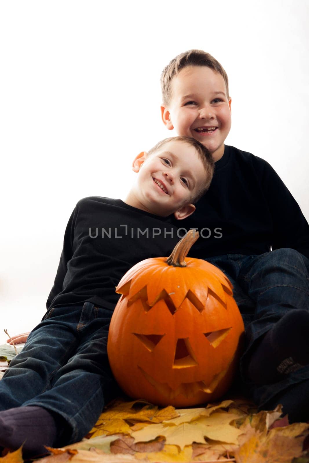 A cute photograph of a two boys and her Halloween pumpkin