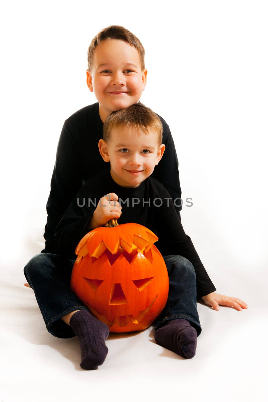 A cute photograph of a two boys and her Halloween pumpkin