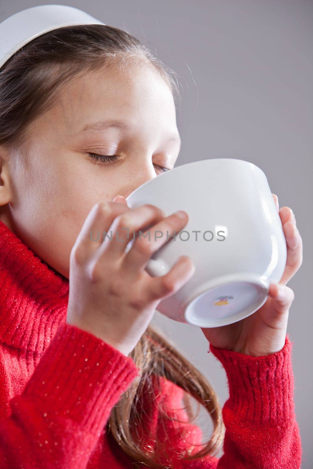 Little girl with her mugful (or cup) drinking her milk