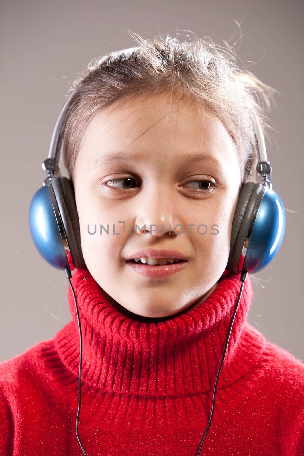 Little girl listening to the music inher blue headphones a little surprised