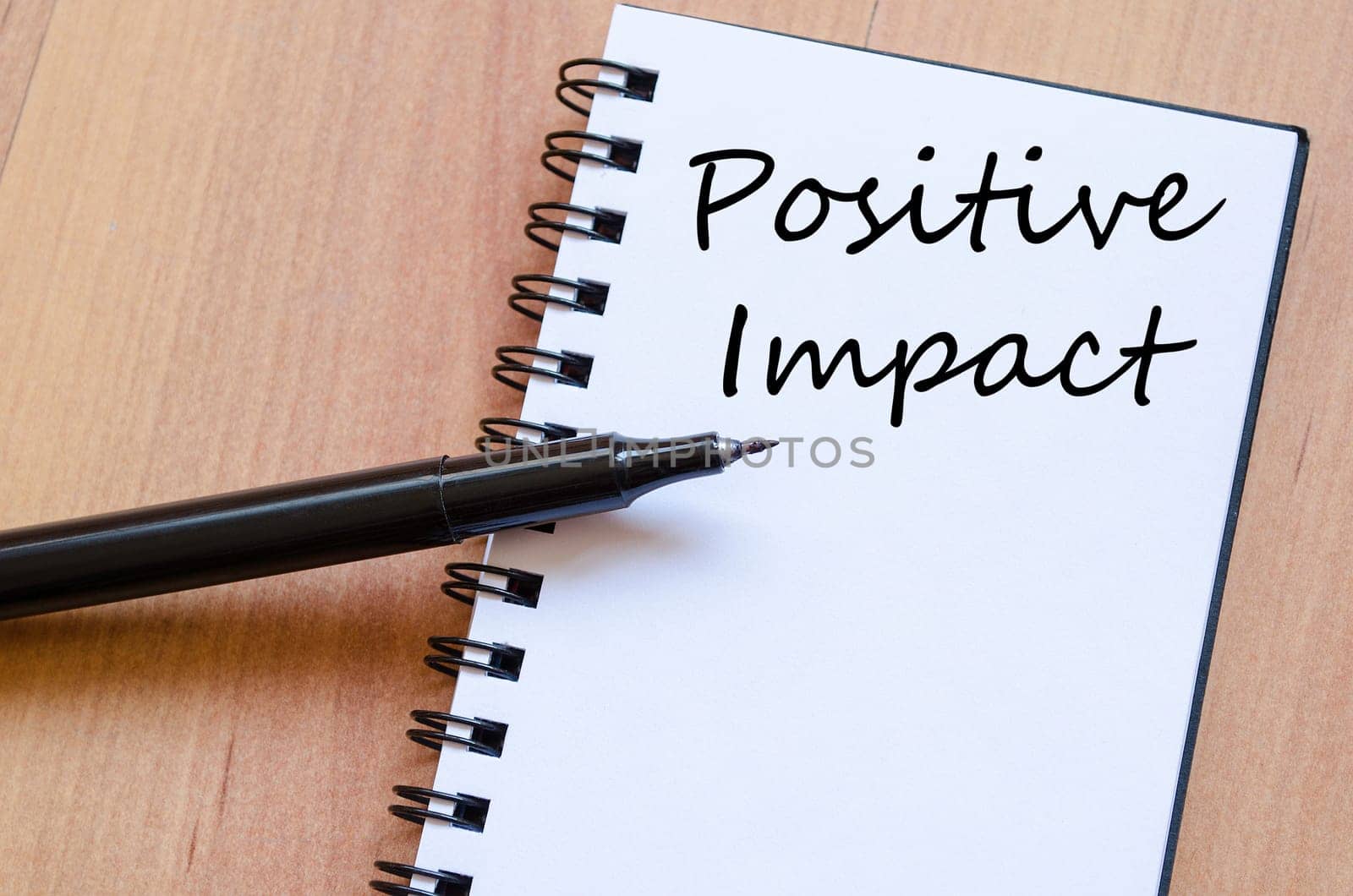 Positive impact text concept write on notebook with pen