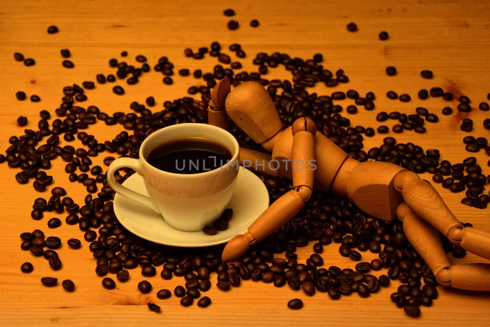 Cup of coffee on wooden table with coffee beans and wooden figure is next to it