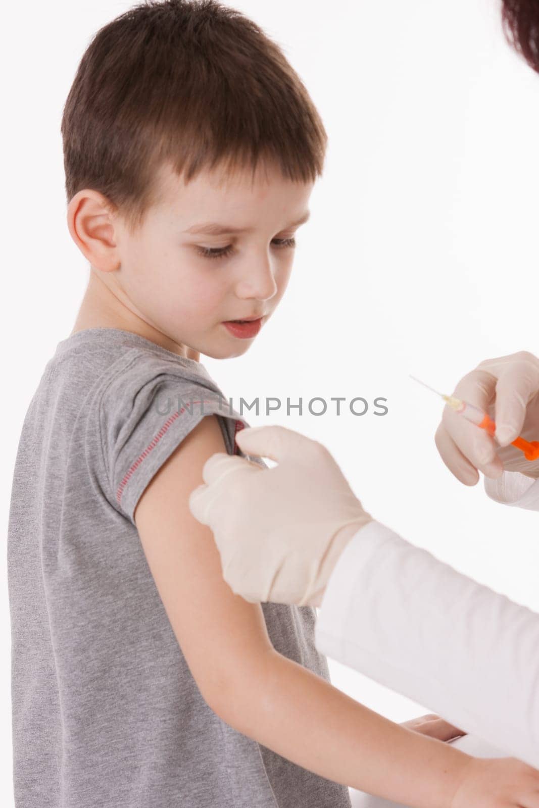 Doctor giving a child injection in arm on isolated image.
