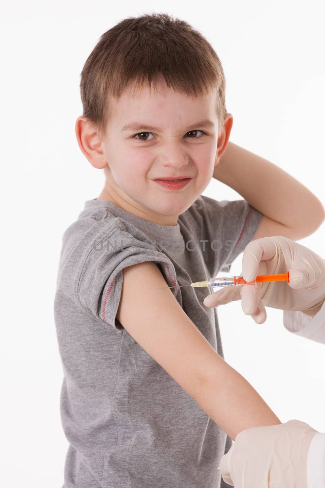 Doctor giving a child injection in arm on isolated image.