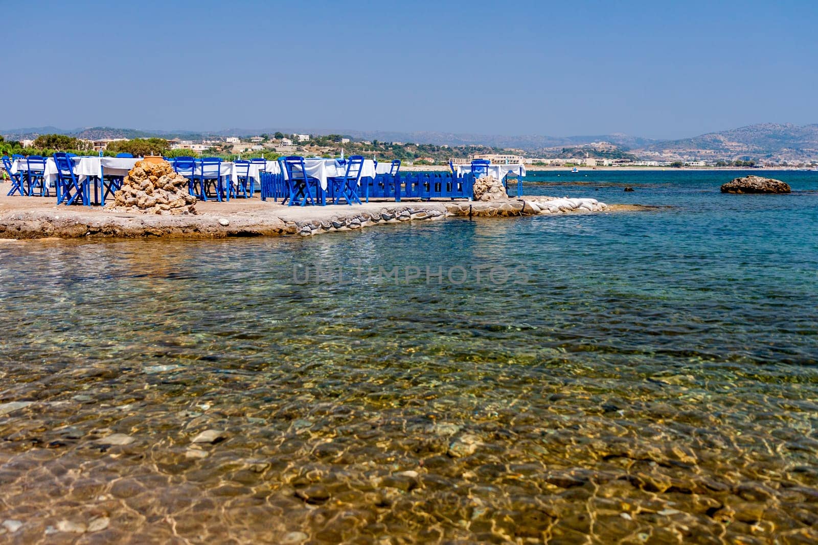 Tables with chairs in traditional Greek tavern in Kolympia town on coast of Rhodes island, Greece.