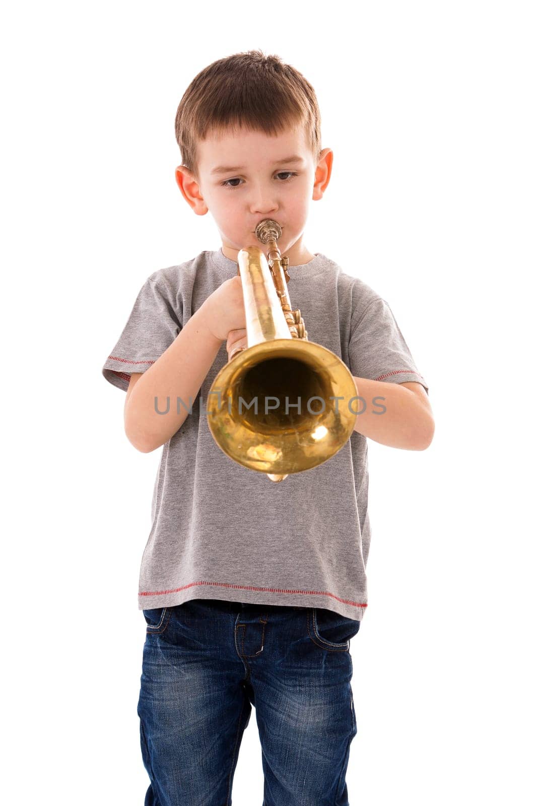 young boy blowing into a trumpet against white background