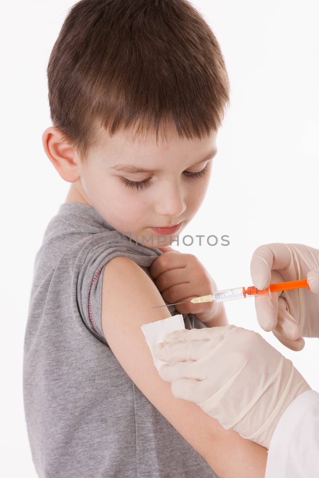 Doctor giving a child injection in arm on isolated image.