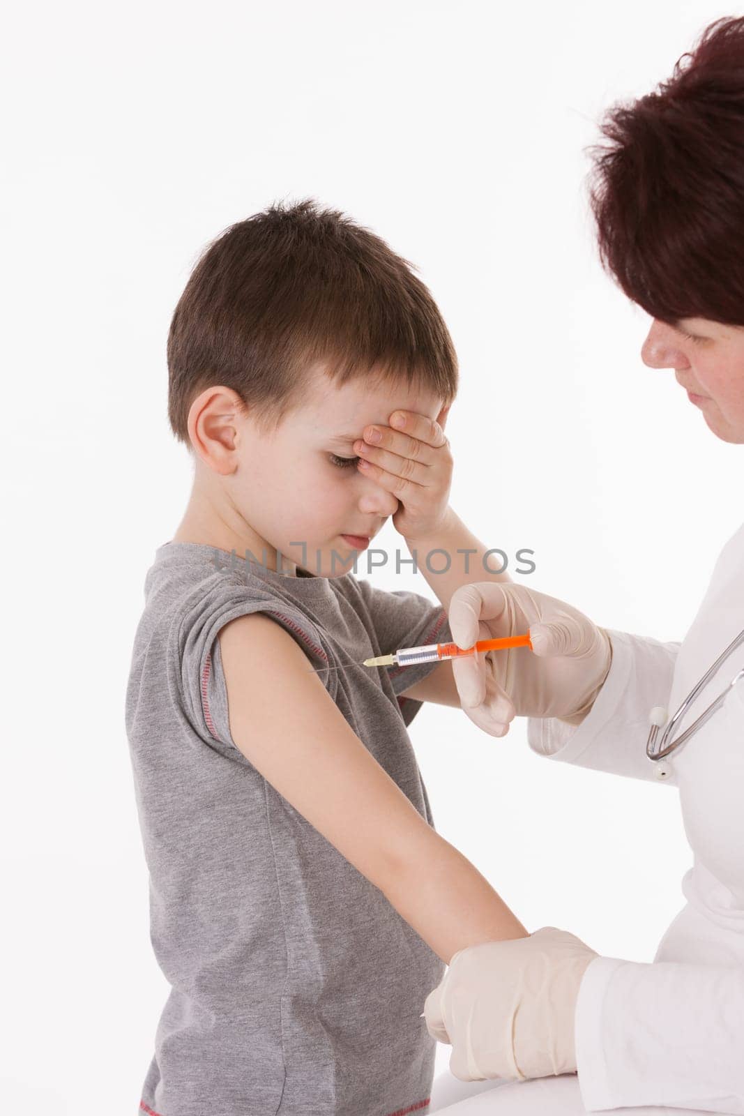 Doctor giving a child injection in arm on isolated image.