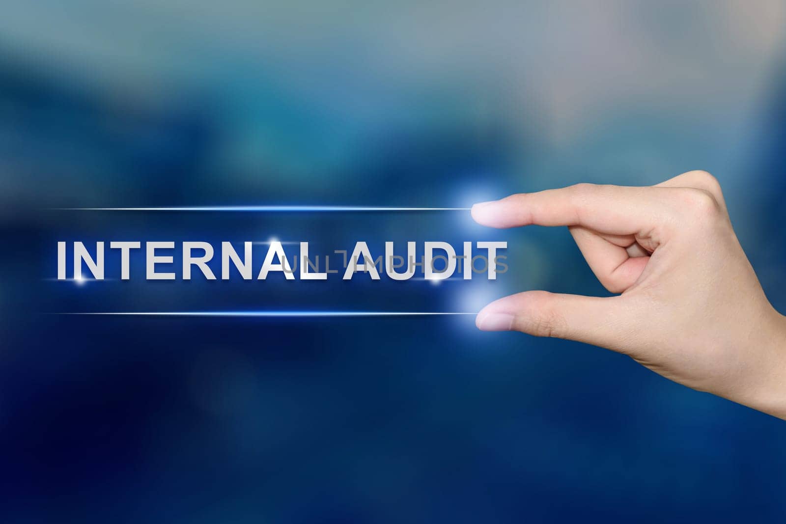hand pushing internal audit button on blurred blue background