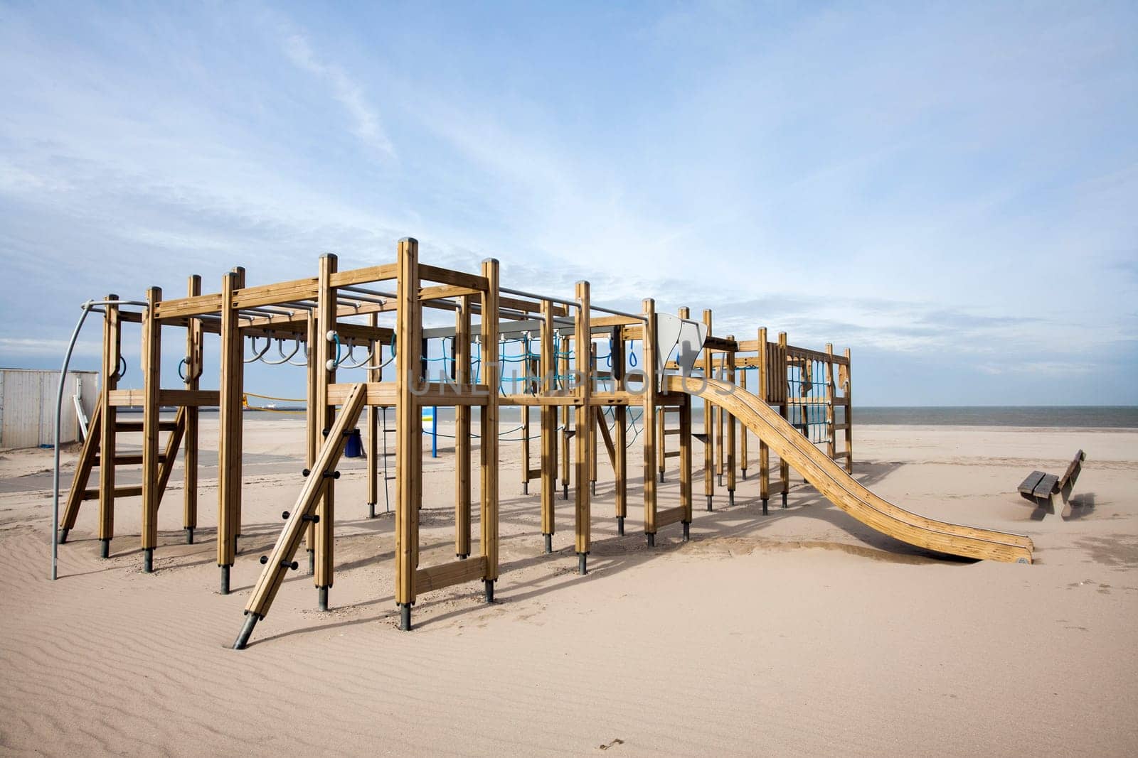 Wooden playground on the beach and a bench