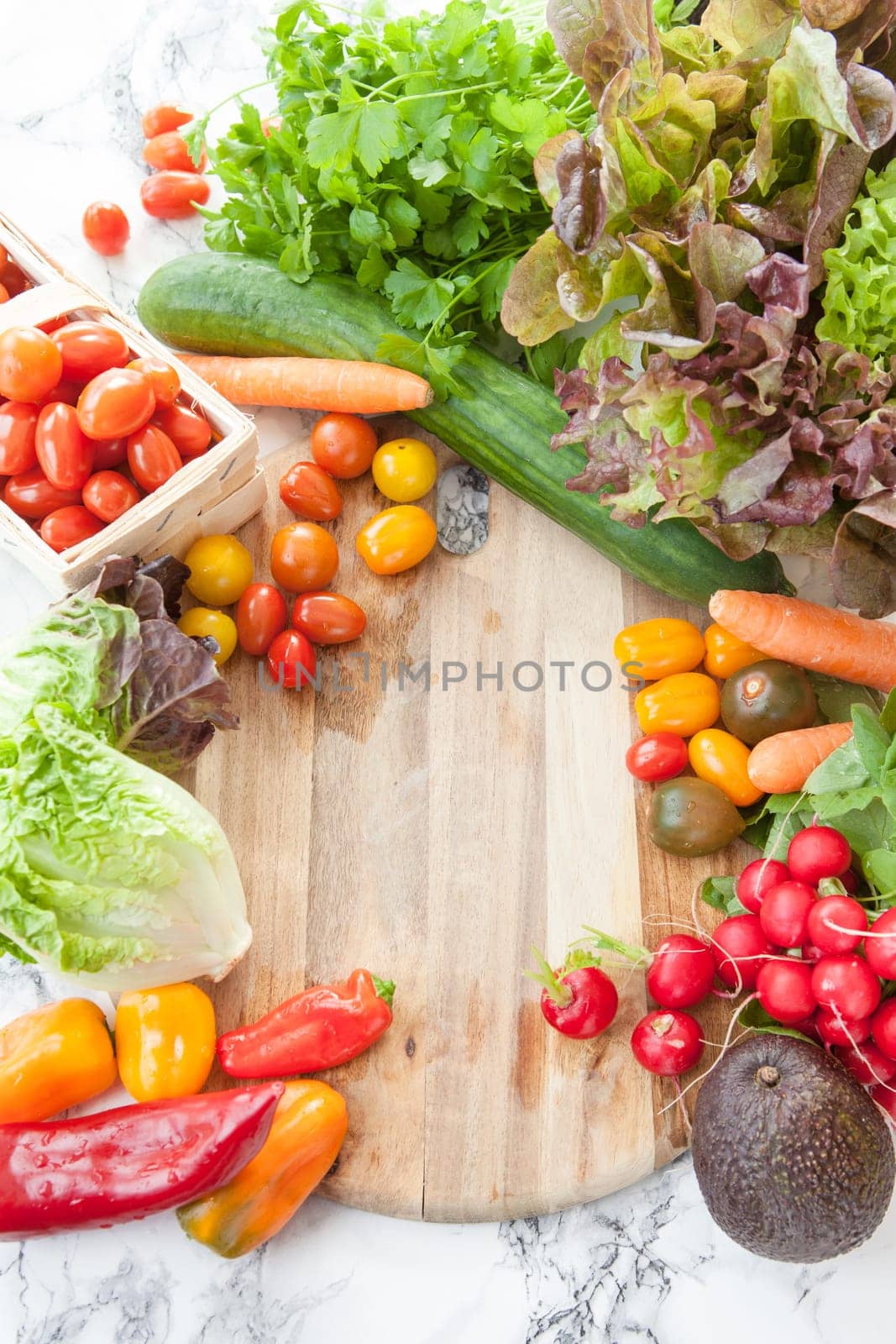 Fresh vegetables for a salad around rustic wood cutting board