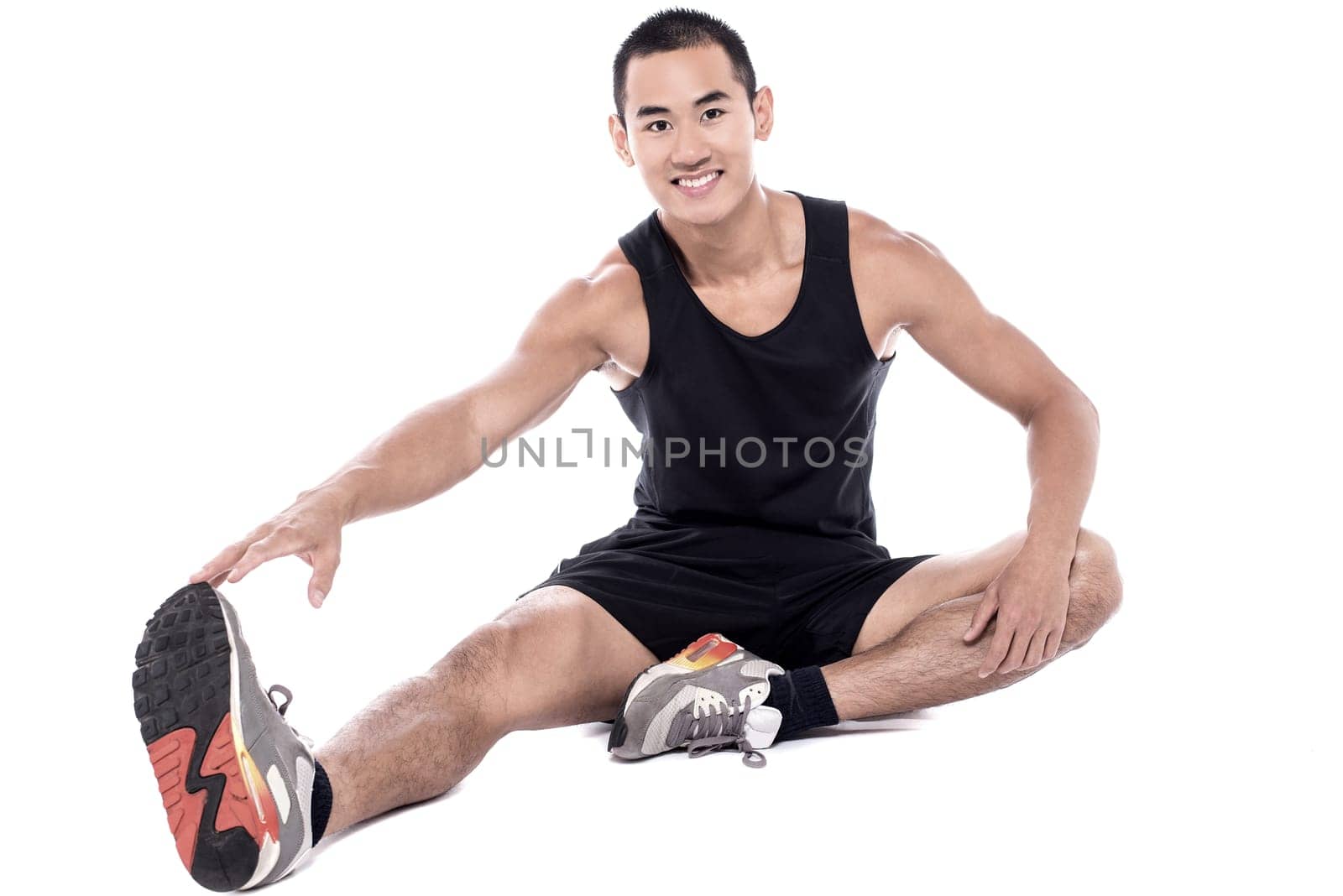 Young fitness man sitting and making stretching exercises