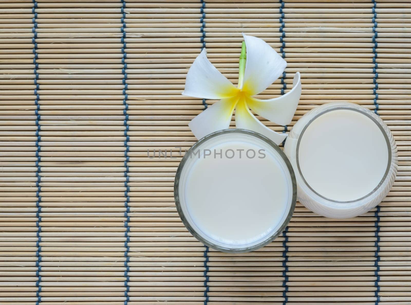 Fresh Soy milk (Soya milk) on bamboo place mat with white plumeria flower. Traditional staple of East Asian cuisine