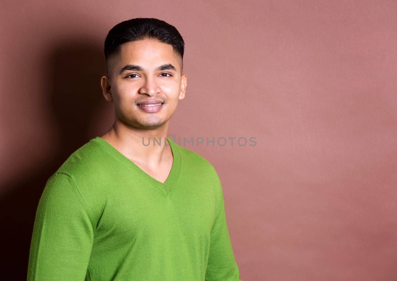 young casual man wearing green on brown background