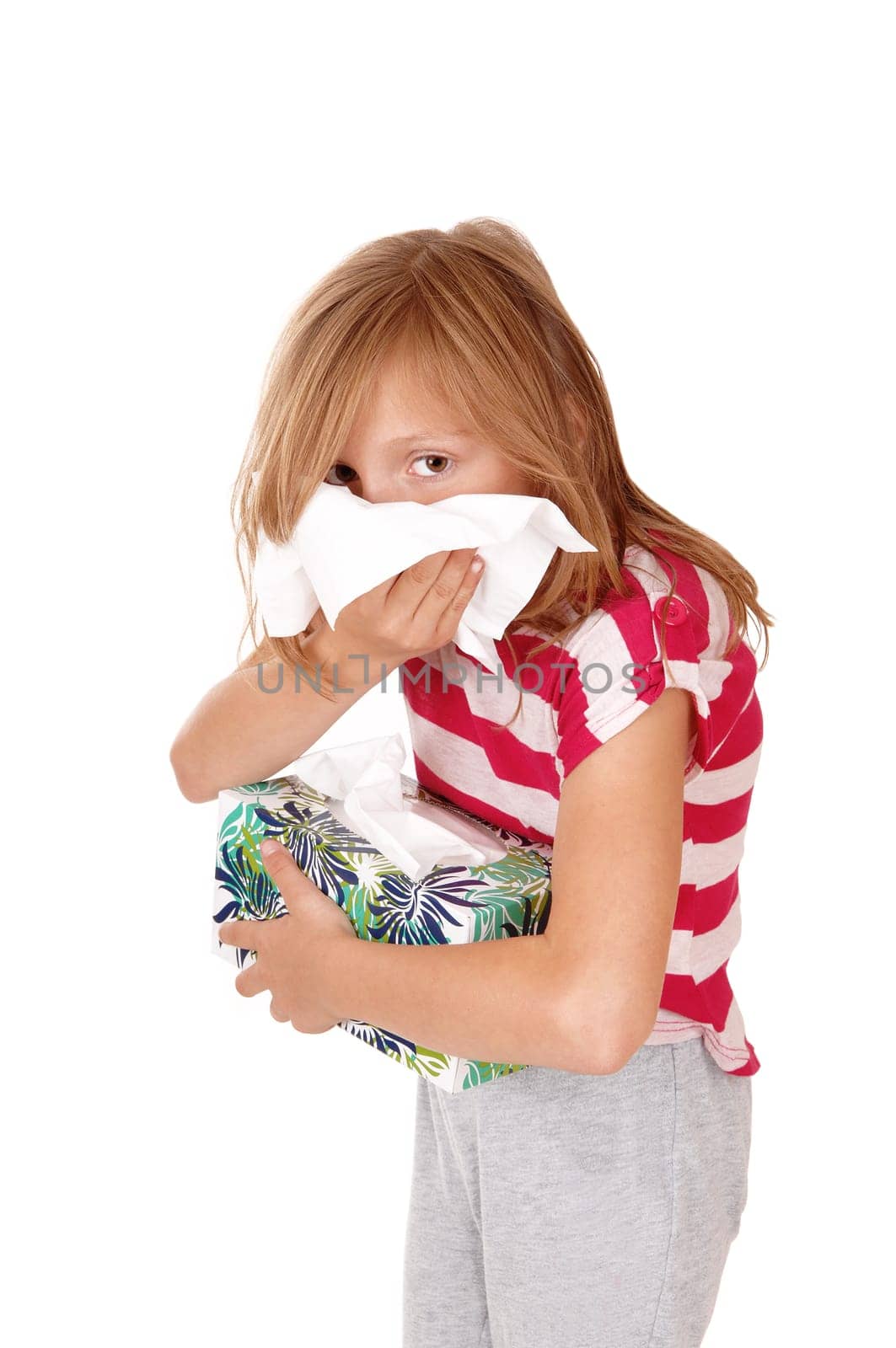 A lovely young blond girl blowing her running nose, holding a tissue box.in her hand, isolated for white background..