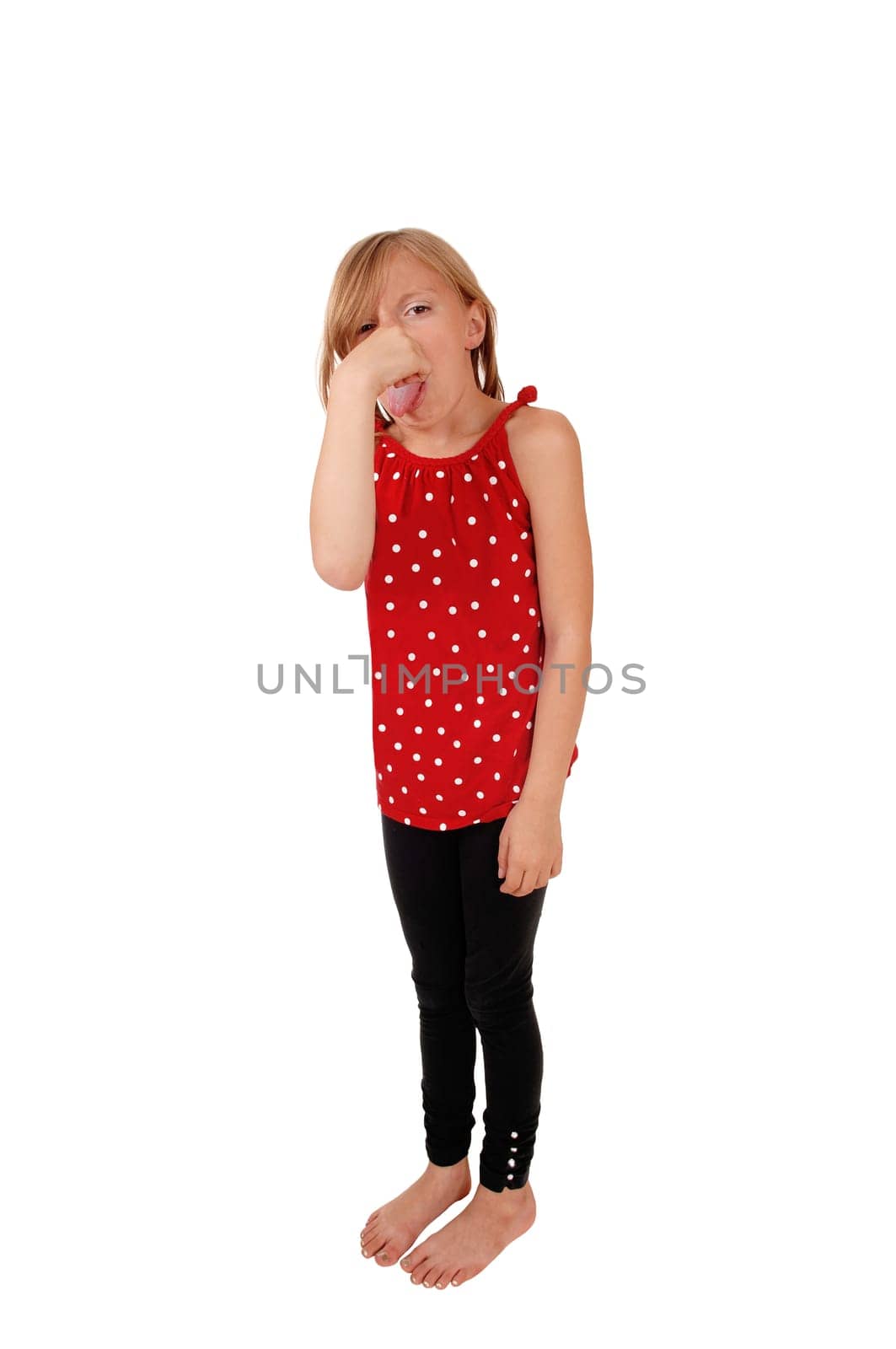 A young eight year old girl standing for white background, holding her.nose for the bad smell and with her tongue out..