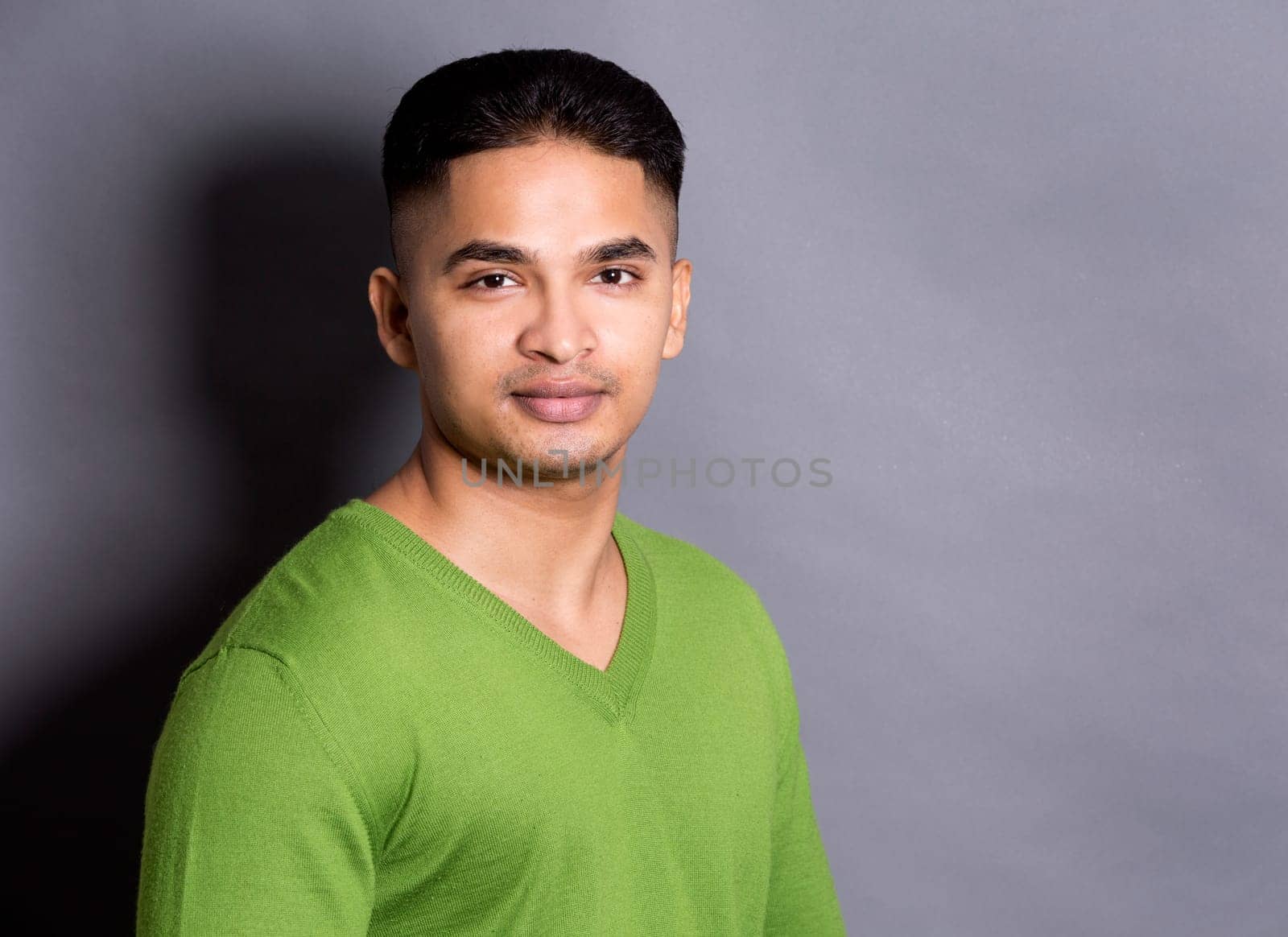 young casual man wearing green on grey background
