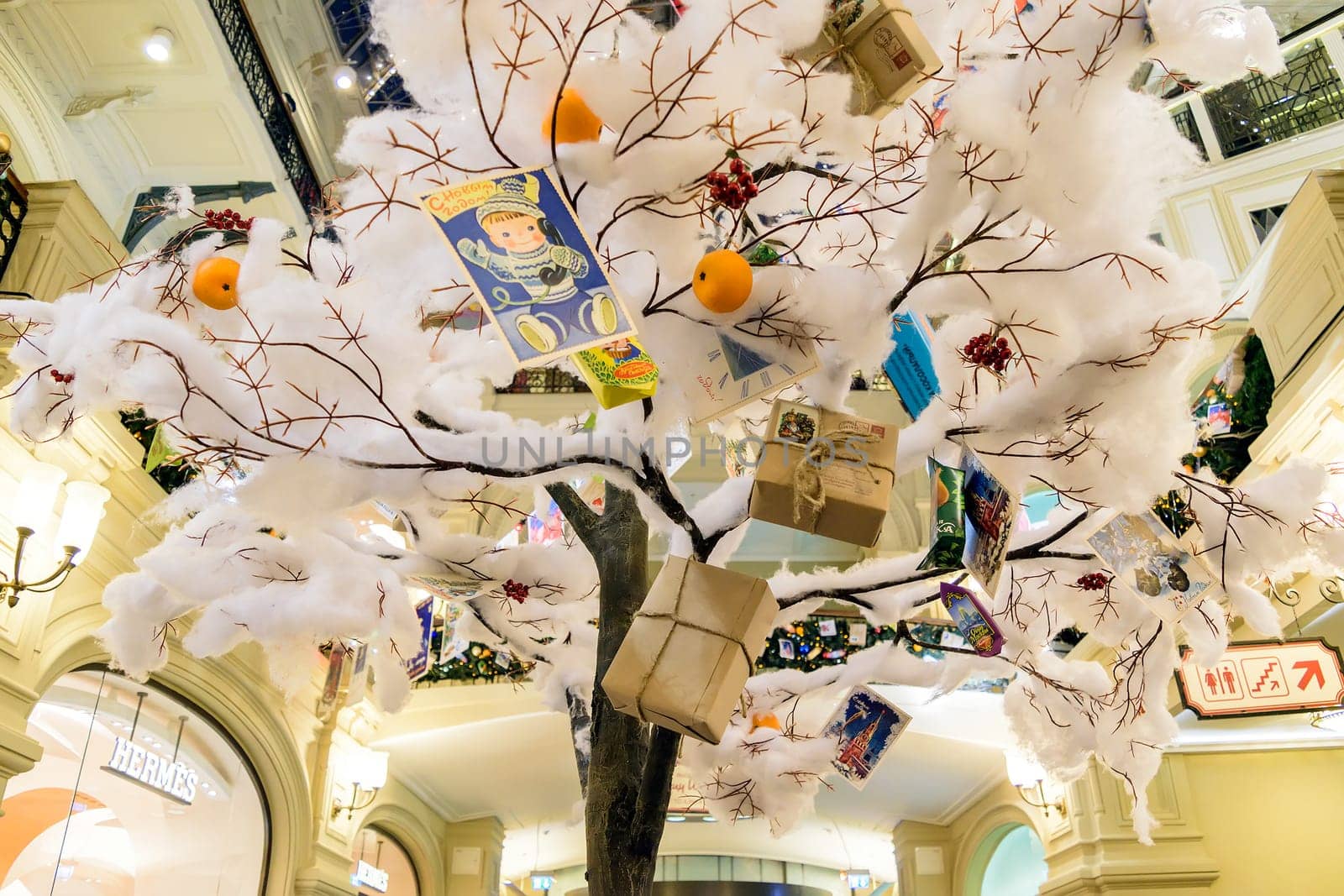 Moscow, Russia - January 05, 2016: Christmas toys and gifts hanging on an artificial tree covered with snow cotton wool