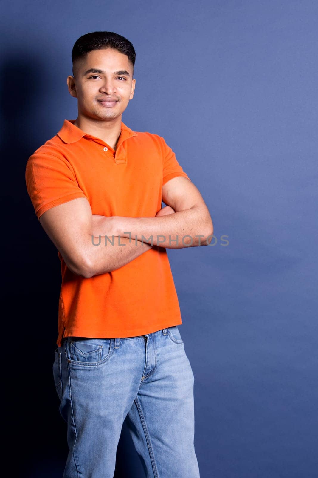 young casual man wearing orange tshirt on blue background