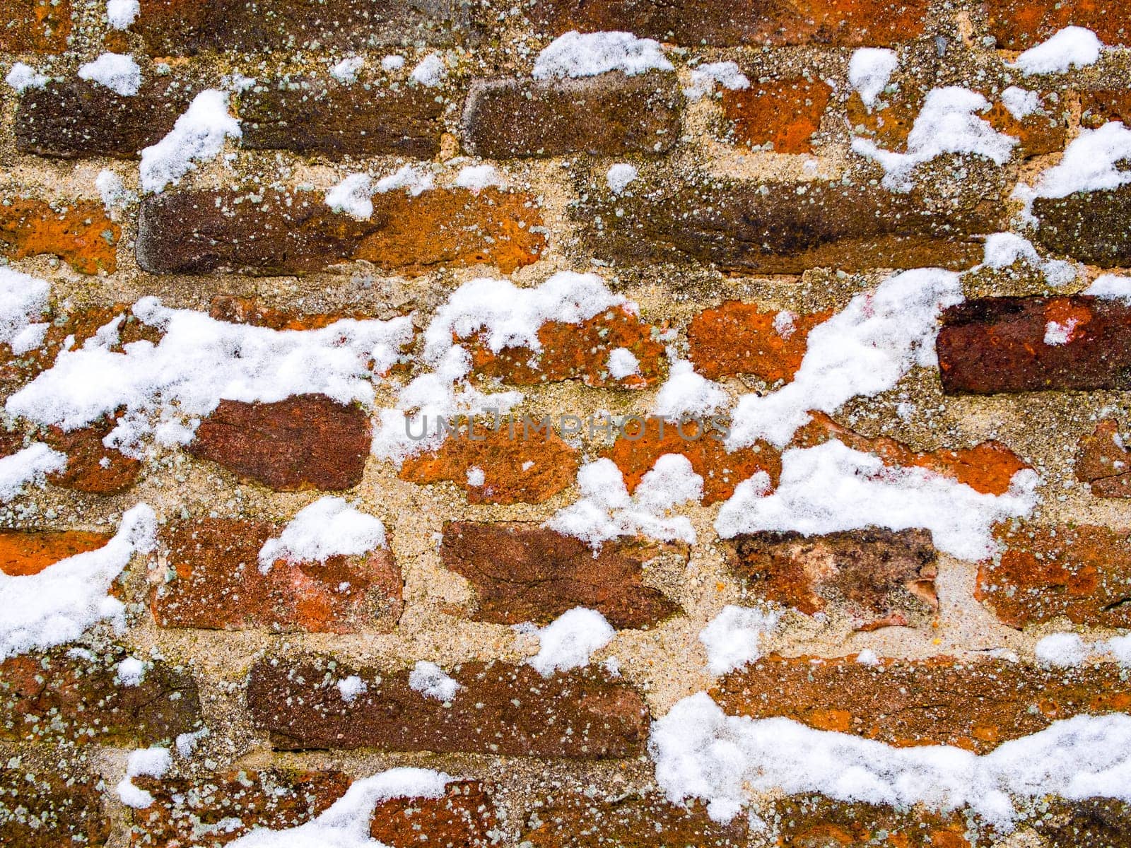 Detail of red brick and concrete wall lightly covered with snow flakes, winter time illustration, background, pattern