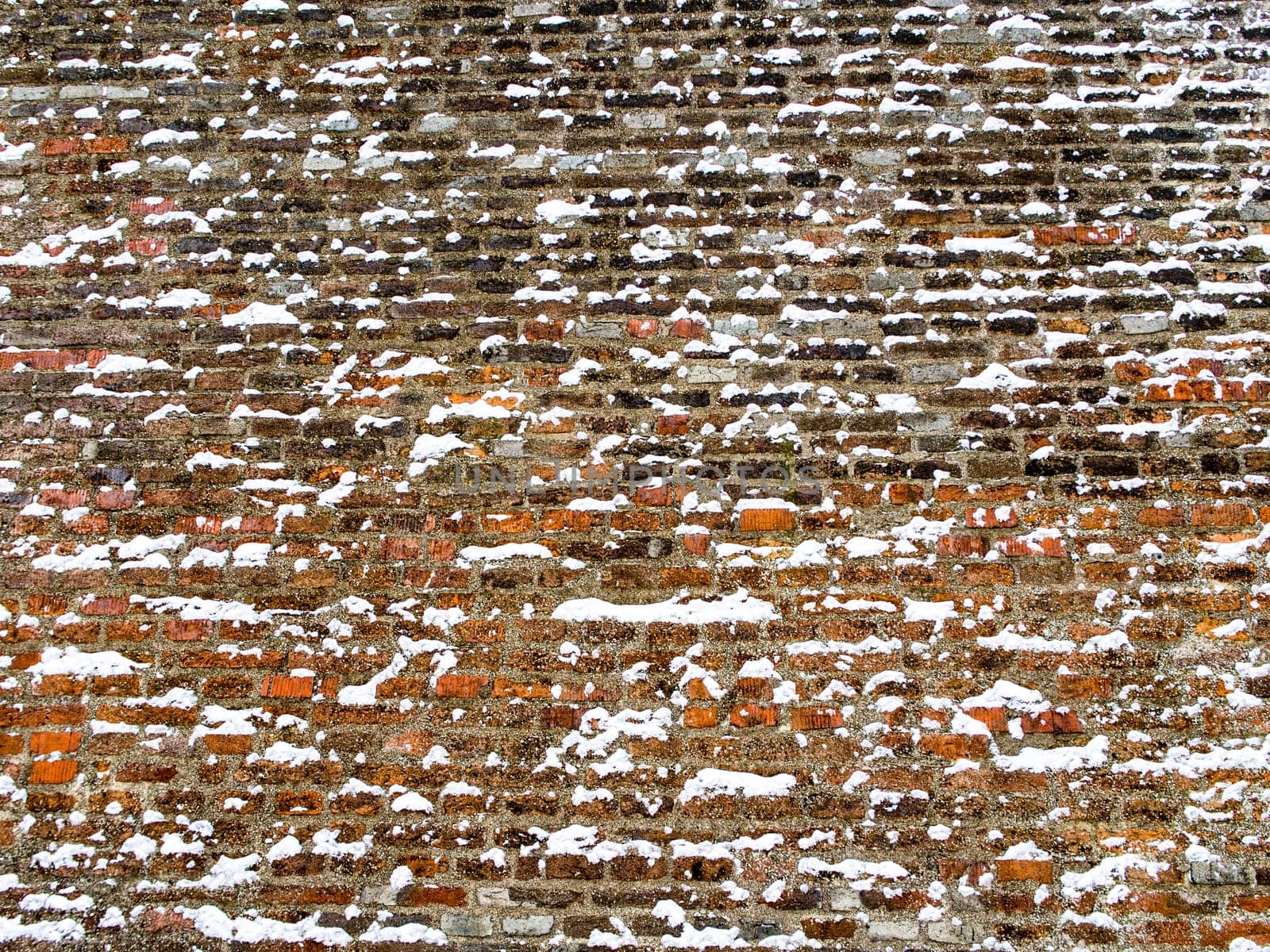 Detail of red brick and concrete wall lightly covered with snow flakes, winter time illustration, background, pattern