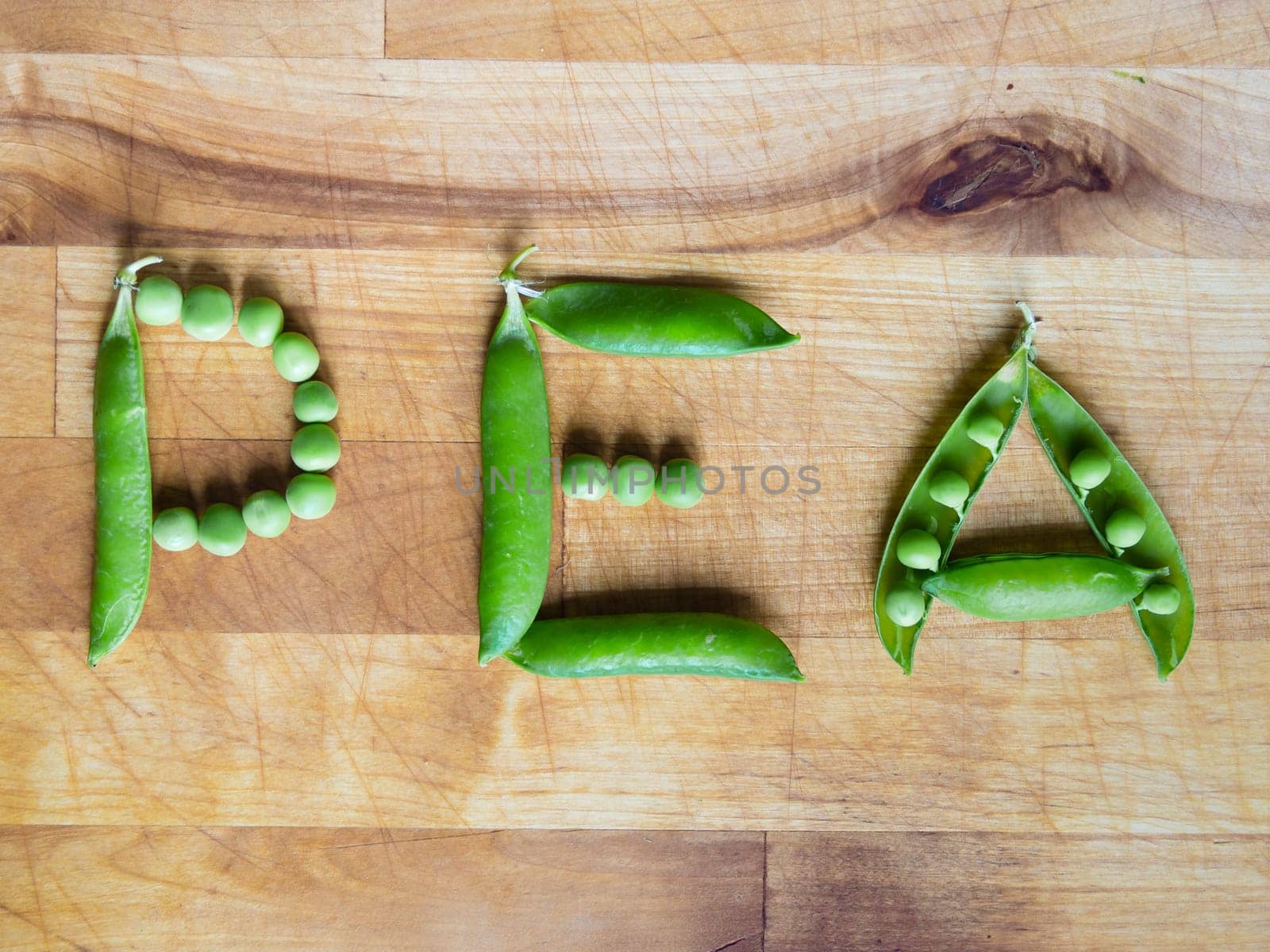 Word PEA created with peas on a wooden board