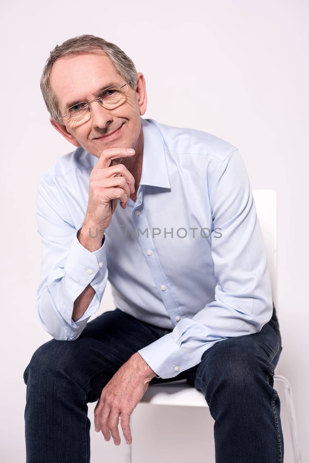 Thoughtful senior man siting on white chair